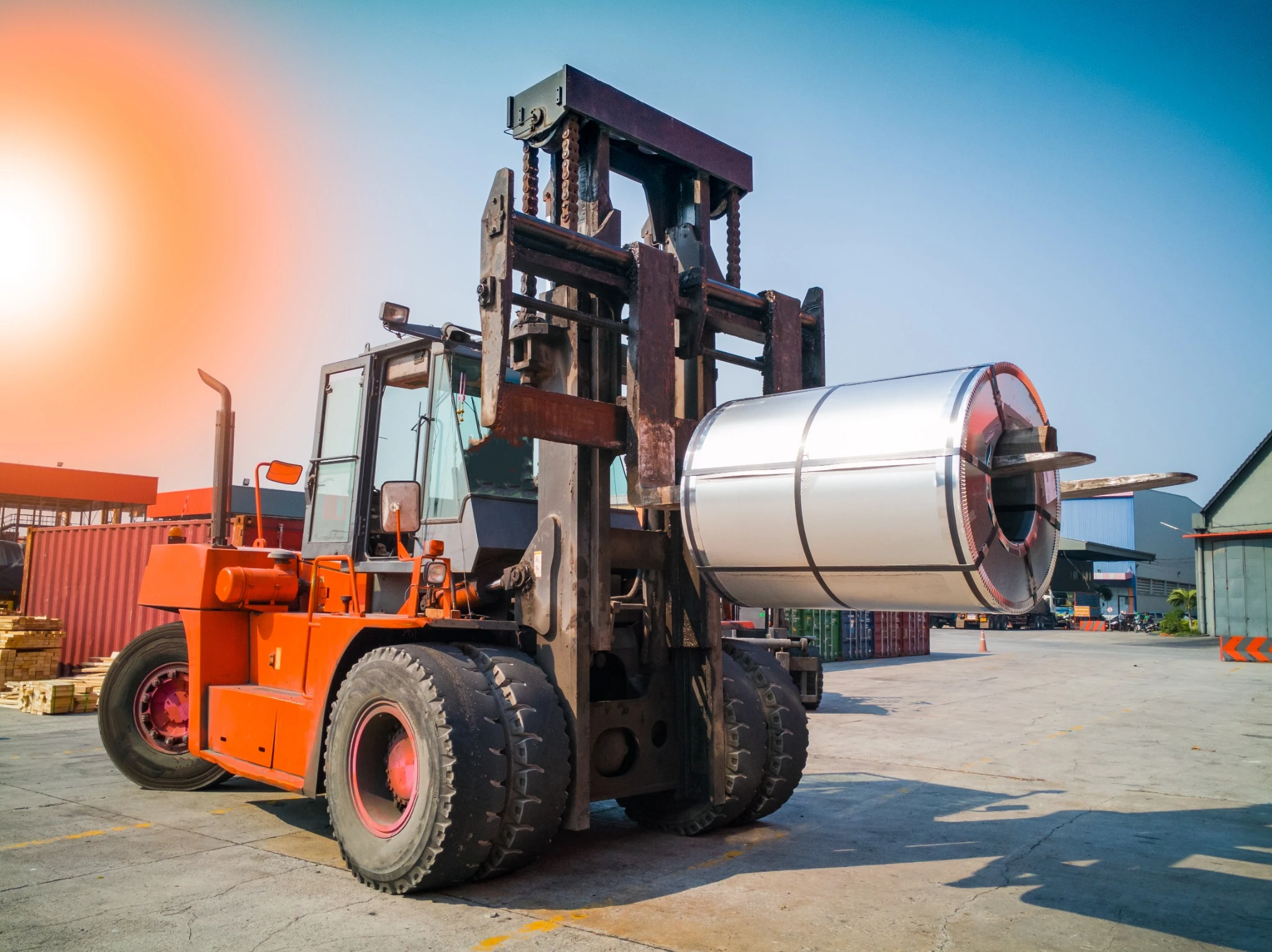 A heavy-duty forklift equipped with a coil handling attachment transports a steel roll in Ontario, Canada.